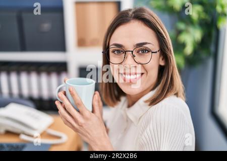 Jeune belle femme hispanique travailleur d'affaires buvant du café au bureau Banque D'Images