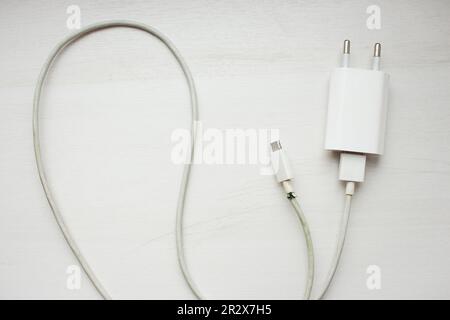 Fiche électrique sur fond blanc. Cordon d'alimentation avec chargeur cassé. Cordon usb cassé. Smartphone. Câble pour téléphone portable. Banque D'Images