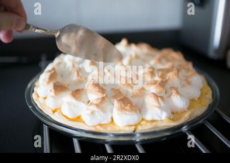 Main humaine caucasienne sur le point de servir une tarte au citron maison Banque D'Images