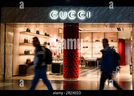 Le logo de la marque italienne de mode de luxe Gucci est visible sur le dessus d'un magasin à l'intérieur de l'aéroport de Zurich quand les gens passent par lui. Banque D'Images