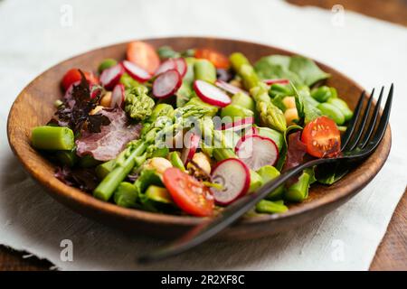 Salade de printemps saine aux asperges vertes, aux haricots fava, aux pois chiches et aux radis. Banque D'Images