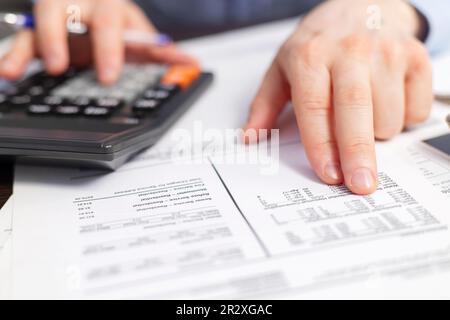 Homme d'affaires utilisant la calculatrice pour calculer les factures à la table dans le bureau Banque D'Images