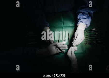 Prise de vue à angle bas dans la salle d'opération, l'assistant remet des outils aux chirurgiens pendant la chirurgie Banque D'Images