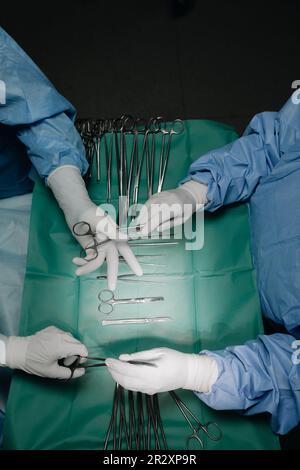 Mains de l'infirmière dans la salle d'opération qui remet les instruments au chirurgien pendant l'opération Banque D'Images