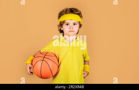 Petit ballon de basket-ball. Sport enfant garçon en uniforme jouant au basket-ball. Sport professionnel. Entraînement au basket-ball. Enfant mignon Banque D'Images