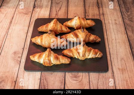 Un plateau avec de délicieux croissants fraîchement sortis du four sur une table en bois Banque D'Images