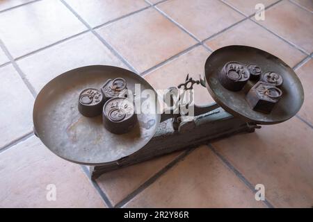 une balance ancienne avec des poids de différentes tailles des deux côtés, sur un sol rustique, vieux poids, ancienne balance vintage, anciennes échelles sur une surface de tuile, s Banque D'Images