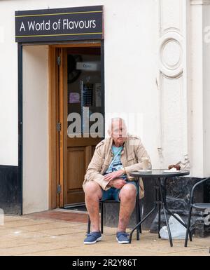 20 mai 2023. High Street, Nairn, Écosse. C'est un homme assis dans un café appelé un monde de saveurs. Banque D'Images