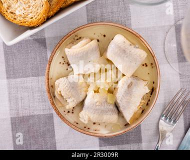 Sur une assiette de nappe à carreaux avec hors-d'œuvre - rouleaux de filet de hareng salé de l'Atlantique avec oignons Banque D'Images