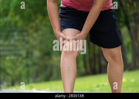 Gros plan d'une jeune athlète féminine souffrant de douleurs au genou après l'exercice. Athlète féminine souffrant de douleurs aux jambes pendant l'exercice dans le parc. Concept de blessure d'exercice Banque D'Images