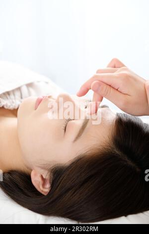 Femme recevant une acupression entre les yeux dans une clinique d'acupuncture Banque D'Images