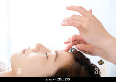 Femme recevant une acupression entre les yeux dans une clinique d'acupuncture Banque D'Images