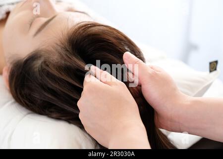 Mains des femmes et des praticiens recevant le massage du cuir chevelu Banque D'Images