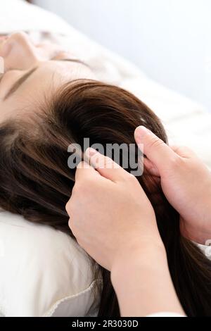 Mains des femmes et des praticiens recevant le massage du cuir chevelu Banque D'Images