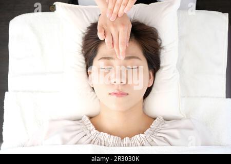 Femme recevant une acupression entre les yeux dans une clinique d'acupuncture Banque D'Images