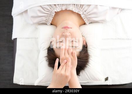 Femme recevant une acupression entre les yeux dans une clinique d'acupuncture Banque D'Images