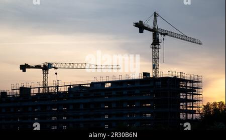 22 mai 2023, Saxe, Schkeuditz: Des grues se tiennent derrière la coque d'un immeuble de bureaux sur un chantier de construction à l'aéroport de Leipzig/Halle à Schkeuditz. Au début de la nouvelle semaine, selon le DWD, il restera chaud en Allemagne après le week-end estival, mais il devrait devenir de plus en plus humide et orageux. Lundi commencera dans la moitié est du pays avec des cieux ensoleillés à nuageux et, à part quelques orages sur les montagnes, sec. Dans l'ouest de l'Allemagne, elle sera également en partie claire au début, mais au cours de la journée, de lourds nuages de printemps se formeront. Photo: Hendrik Banque D'Images