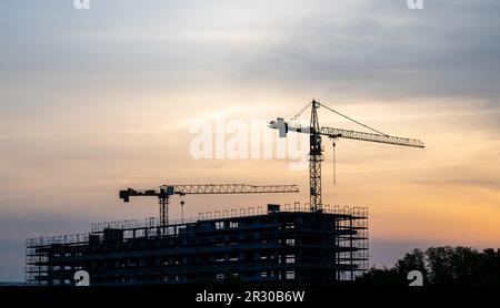 22 mai 2023, Saxe, Schkeuditz: Des grues se tiennent derrière la coque d'un immeuble de bureaux sur un chantier de construction à l'aéroport de Leipzig/Halle à Schkeuditz. Au début de la nouvelle semaine, selon le DWD, il restera chaud en Allemagne après le week-end estival, mais il devrait devenir de plus en plus humide et orageux. Lundi commencera dans la moitié est du pays avec des cieux ensoleillés à nuageux et, à part quelques orages sur les montagnes, sec. Dans l'ouest de l'Allemagne, elle sera également en partie claire au début, mais au cours de la journée, de lourds nuages de printemps se formeront. Photo: Hendrik Banque D'Images