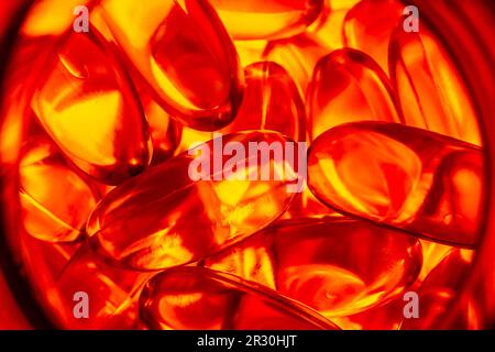 beaucoup de capsules de gélatine jaune sur fond rouge. vitamines omega, gros plan, macro. Banque D'Images