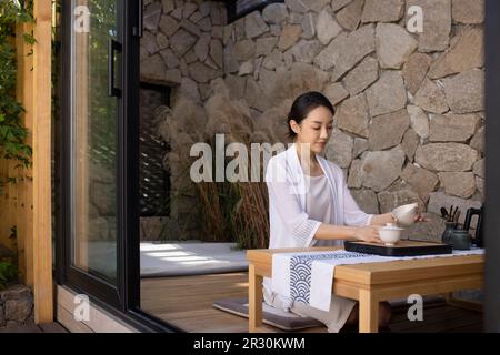 Élégante jeune femme chinoise qui boit du thé dans le salon de thé Banque D'Images