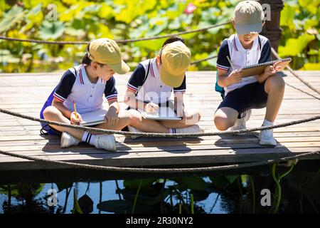 Les enfants de l'école chinoise sont joyeux et s'attirent dans le parc Banque D'Images