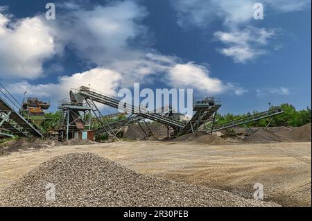 Convoyeur de carrière de gravier de l'industrie Minning. Machines de concassage, concasseur de roche de type cône, transportant la pierre de gravier de granit broyée dans une mine de carrière à ciel ouvert Banque D'Images