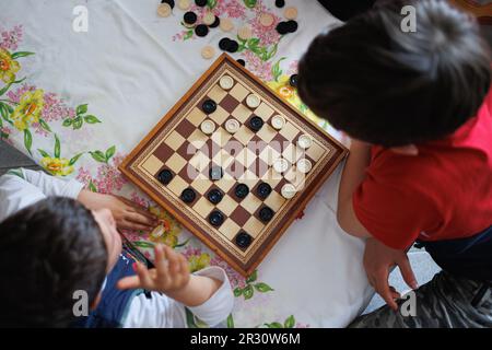 Vue depuis le dessus d'un jeu de dames et de deux enfants jouant aux dames. Banque D'Images