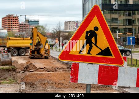 Les hommes au travail signent sur le chantier de construction de travaux routiers et d'entretien des routes avec des camions et des machines en arrière-plan, priorité sélective Banque D'Images