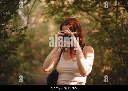 Femme photographiant avec un appareil photo en forêt Banque D'Images