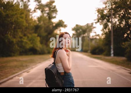 Jeune femme marchant sur la route de campagne Banque D'Images