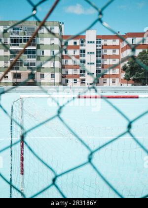 But de football sur terrain bleu en travers de la clôture avec des bâtiments en arrière-plan Banque D'Images