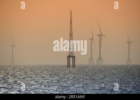 Les ventilateurs des éoliennes tournent au-dessus de la mer étincelante. Un parc éolien offshore au large de la côte nord-ouest de Taïwan. Un de la puissance verte. Banque D'Images