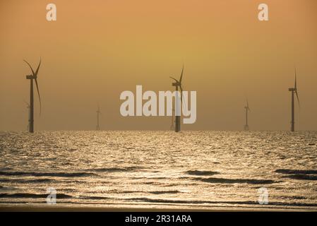 Les ventilateurs des éoliennes tournent au-dessus de la mer étincelante. Un parc éolien offshore au large de la côte nord-ouest de Taïwan. Un de la puissance verte. Banque D'Images