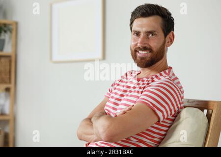 Portrait de beau barbu homme dans un fauteuil à la maison, espace pour le texte Banque D'Images