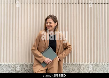 Portrait d'une femme d'affaires souriante dans un costume debout à l'extérieur avec une tablette numérique Banque D'Images