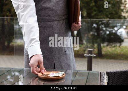 Garçon prenant des conseils de table en bois dans le café extérieur, à proximité Banque D'Images
