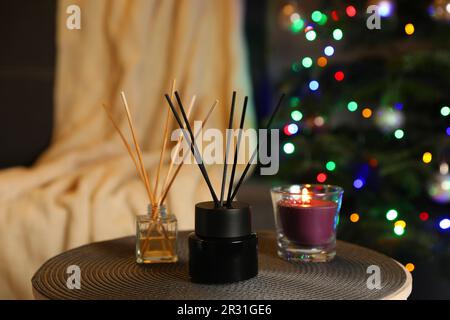 Désodorisants en roseau aromatique et bougie sur une table dans une chambre confortable Banque D'Images