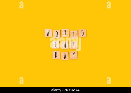 Journée mondiale du chat. Citation faite de blocs de bois avec des lettres sur fond jaune. Banque D'Images