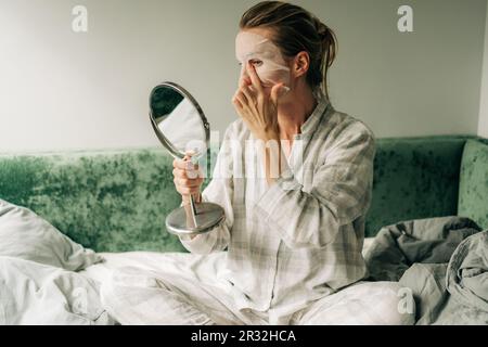 Une femme fait une procédure de beauté de soin à la maison, un masque cosmétique hydratant pour le visage. Banque D'Images