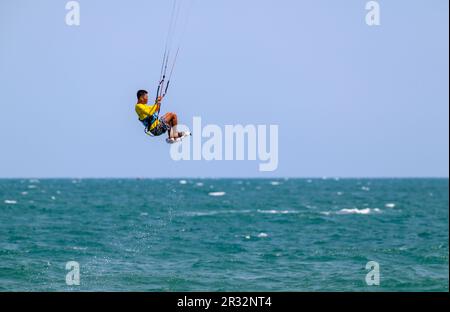 Un kitesurfer saute haut dans l'air au large de la plage à Mui ne, Vietnam. Banque D'Images