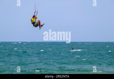 Un kitesurfer saute haut dans l'air au large de la plage à Mui ne, Vietnam. Banque D'Images