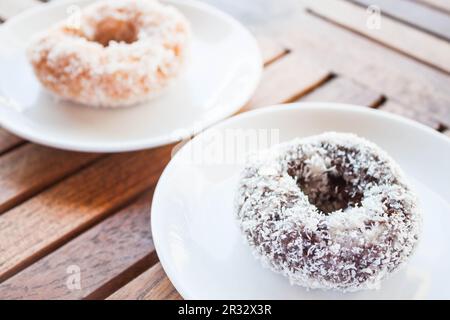 Délicieux beignets de noix de coco au chocolat et à la vanille sur une table en bois Banque D'Images