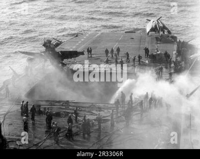 L'équipage des États-Unis Le porte-avions USS Enterprise (CV-6) de la Marine combat des incendies après qu'un kamikaze a frappé l'ascenseur avant le 14 mai 1945. Lorsque le Japon était confronté à la défaite de fin 1944, il a choisi de détruire des navires américains par des attentats-suicides, connus sous le nom de Kamikaze.ces attaques étaient une arme physique et psychologique puissante et ont coulé un total de 47 navires pour un coût de plus de 3000 pilotes et avions. À la fin de 1944, la marine américaine était suffisamment importante pour que les pertes soient insignifiantes et qu’elles n’aient pas modifié le cours de la guerre. Banque D'Images