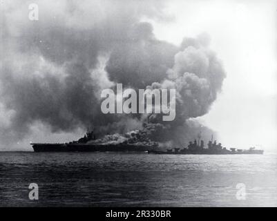 États-Unis Le porte-avions USS Bunker Hill (CV-17) de la Marine après avoir été frappé par deux avions suicide 'Kamikaze' au large d'Okinawa, le 11 mai 1945. Le croiseur léger USS Pasadena est prêt à vous aider. La grève a pris des avions entièrement alimentés et armés sur le pont et a déclenché des feux très dangereux. Bien que fortement endommagé, le navire ne s'est pas effondré et est retourné aux États-Unis pour réparation. Le navire a été mis hors service en 1966 et mis au rebut en 1973. Banque D'Images