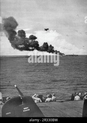 États-Unis Le porte-avions léger USS Belleau Wood (CVL-24) de la Marine a brûlé en arrière après avoir été frappé par un kamikaze, alors qu'elle a été en opération au large de Luzon, aux Philippines, le 30 octobre 1944. Les membres du détachement de la Marine à bord de l'USS Enterprise (CV-6) protègent leurs yeux du soleil pendant qu'ils balayent le ciel pour des avions kamikaze en plongée hors du soleil. Au premier plan se trouve la queue d'un Grumman F6F-5 Hellcat de l'escadron de combat 20 (VF-20). Banque D'Images