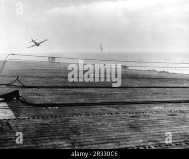 Un pilote japonais kamikaze dans un Mitsubishi A6M5 modèle 52 ('zéro') plonge sur les États-Unis Le transporteur d'escortes de la Marine USS White Plains (CVE-66) le 25 octobre 1944. L'avion a manqué le pont de vol et a touché l'eau juste au large du quartier portuaire du navire. Lorsque le Japon était confronté à la défaite de fin 1944, il a choisi de détruire des navires américains par des attentats-suicides, connus sous le nom de Kamikaze.ces attaques étaient une arme physique et psychologique puissante et ont coulé un total de 47 navires pour un coût de plus de 3000 pilotes et avions. À la fin de 1944, la marine américaine était assez importante pour que les pertes soient insignifiantes et qu'elles n'ont pas fait le contraire Banque D'Images