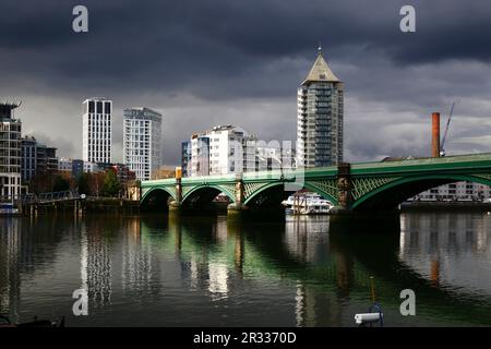 Battersea Railway Bridge / Chelsea River Bridge de l'autre côté de la Tamise et de la Belvedere Tower (Chelsea Harbour) sous un ciel sombre, Londres, Royaume-Uni Banque D'Images