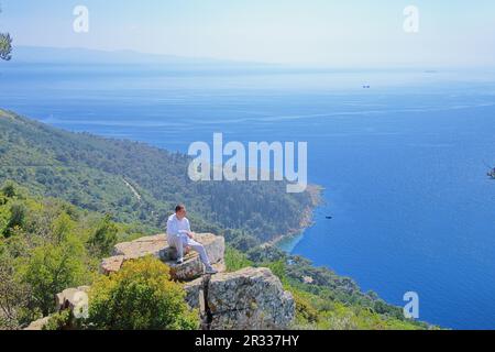 La photo a été prise en Turquie dans l'une des îles des Princes. La photo montre un jeune homme en admirant la mer depuis le haut de la falaise. Banque D'Images