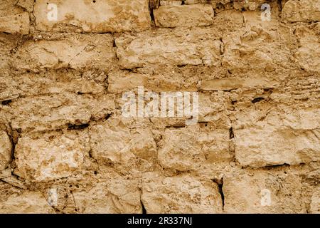 texture horizontale de vieux mur en grès brun grossier, avec vieux plâtre fissuré en argile Banque D'Images