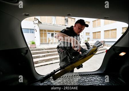 STEPNOHIRSK, UKRAINE - le 19 MAI 2023 - Un agent de droit met un fusil de service dans le coffre de la voiture, Stepnohirsk, région de Zaporizhzhia, sud-est de l'Ukraine Banque D'Images